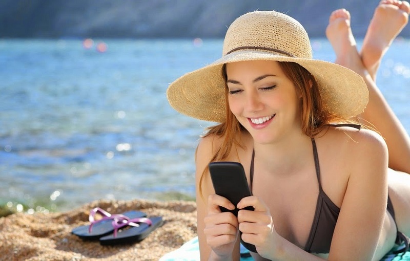 Menina usando o celular em praia