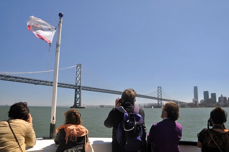 Turistas no cruzeiro por baixo da ponte Golden Gate Bridge em San Francisco
